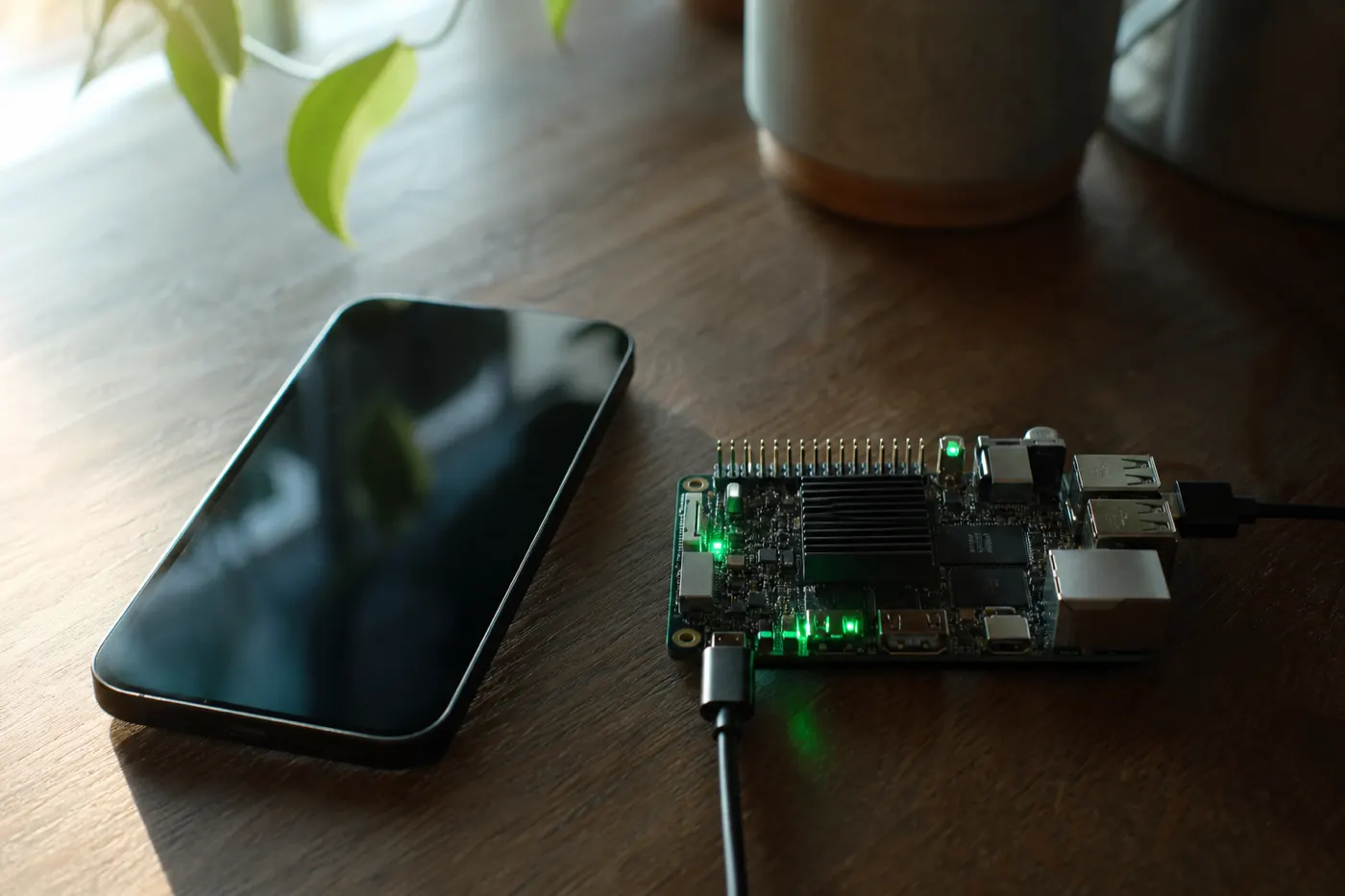 Phone and edge computing board on a wooden table in soft light